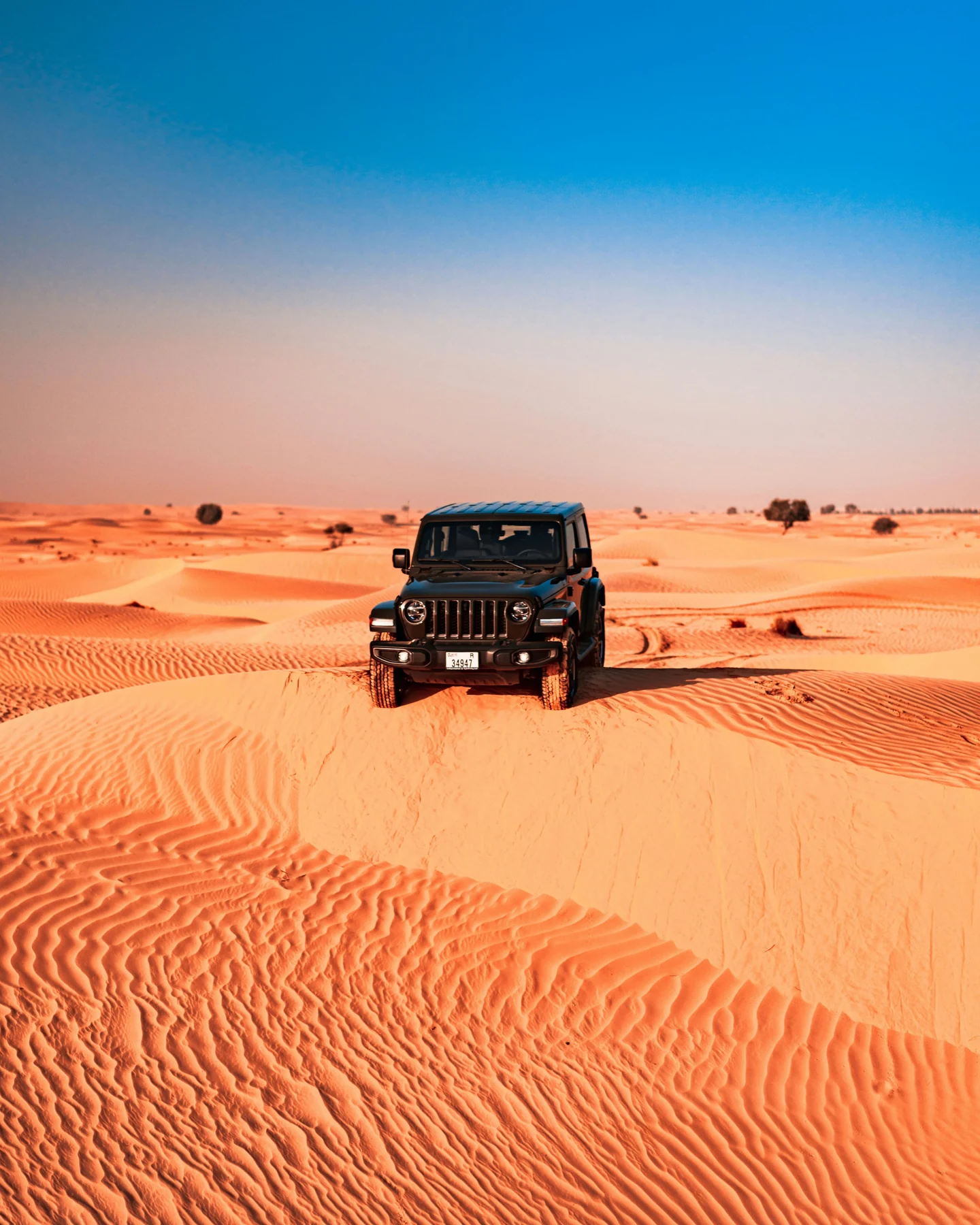 An off-road SUV surrounded by golden desert dunes