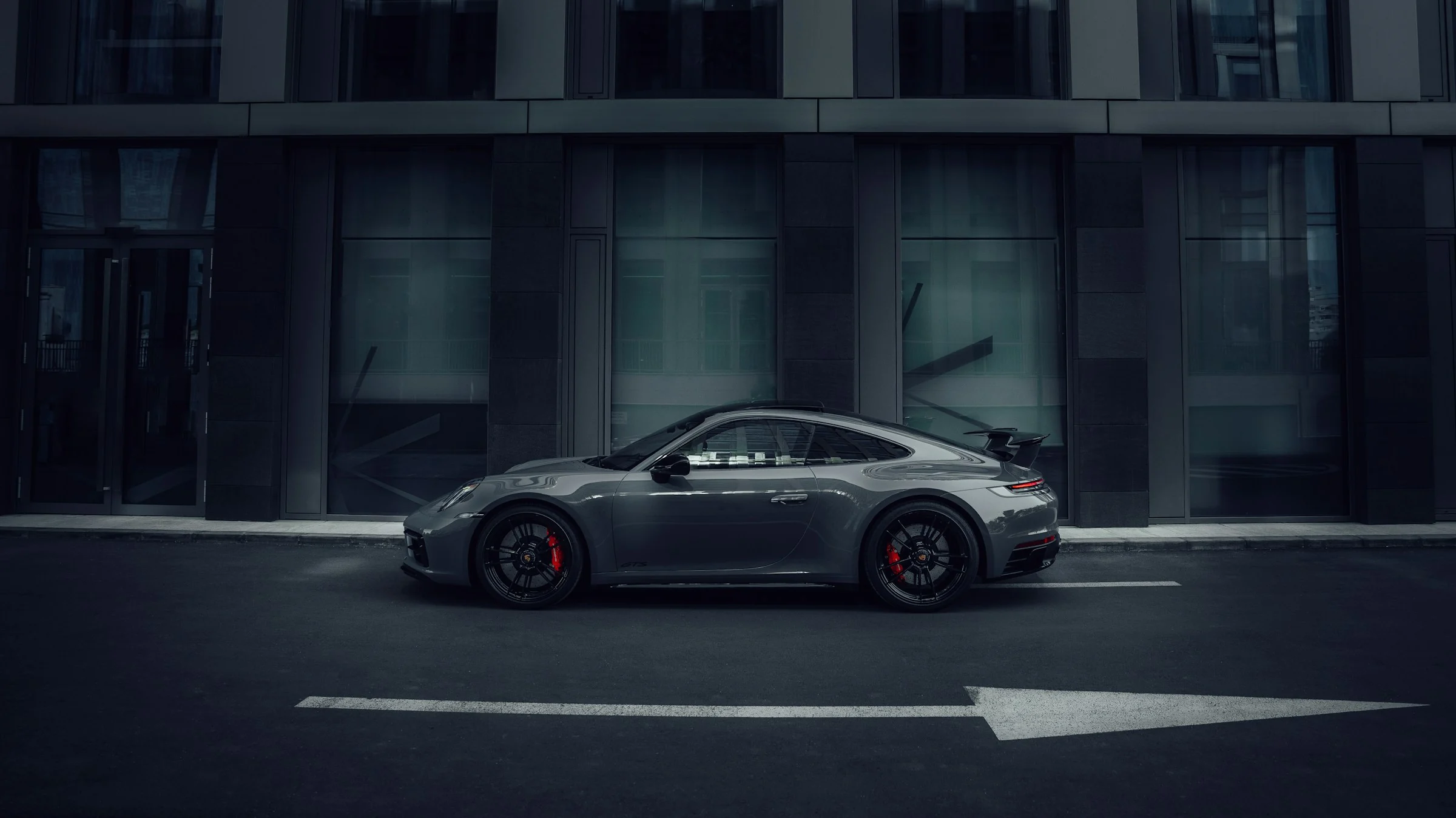 A silver Porsche sports car against contemporary architecture